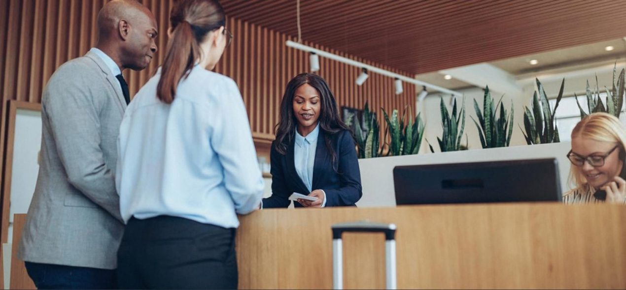Hotel administrator helping two business guests at a modern reception desk in the UAE
