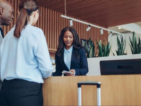 Hotel administrator helping two business guests at a modern reception desk in the UAE