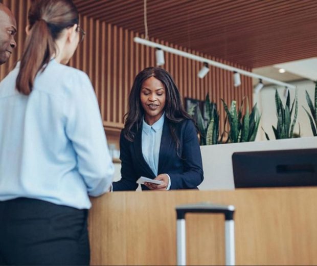 Hotel administrator helping two business guests at a modern reception desk in the UAE